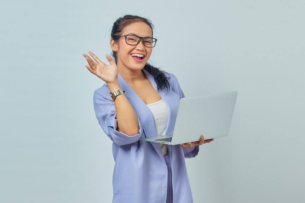 Woman waving on a video call with a laptop